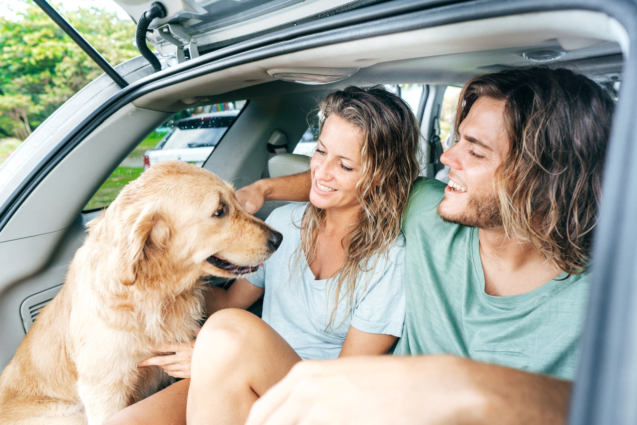 Couple with their dog hanging out in their car.